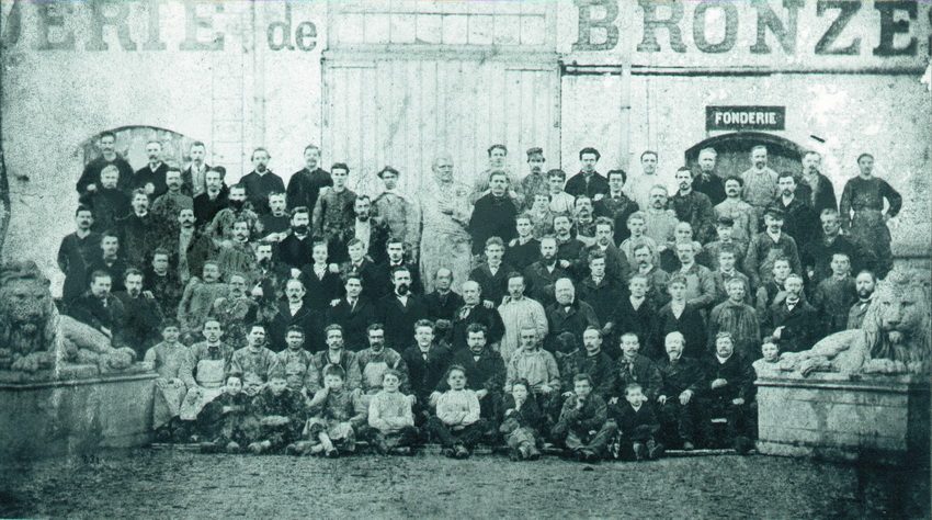 Ancienne photo du personnel de la Compagnie des Bronzes posant devant l'enseigne de la fabrique.