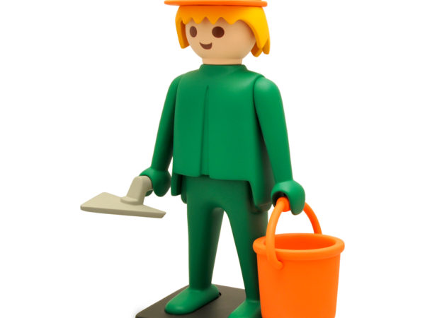 Image d'un personnage playmobil, un casque sur la tête et tenant un seau et une truelle