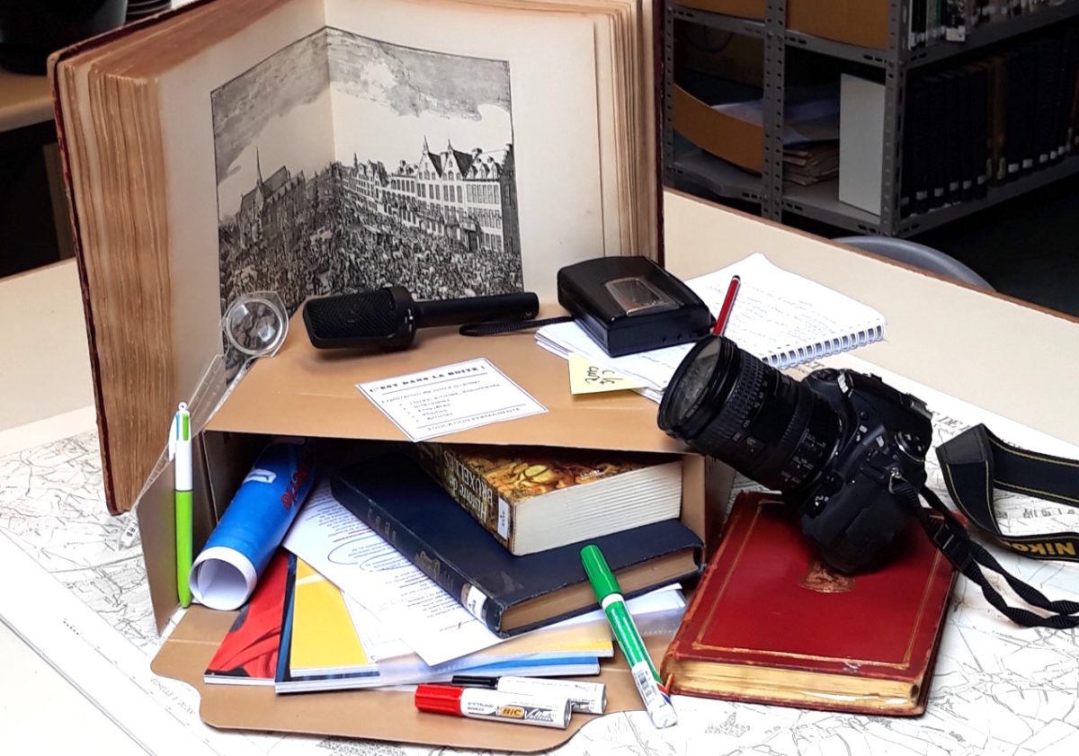 Boîte de centre documentation avec en vrac : livres, revues, brochures, carnet d enotes, bics, loupe, feutres, enregistreur, micro et appareil photo...