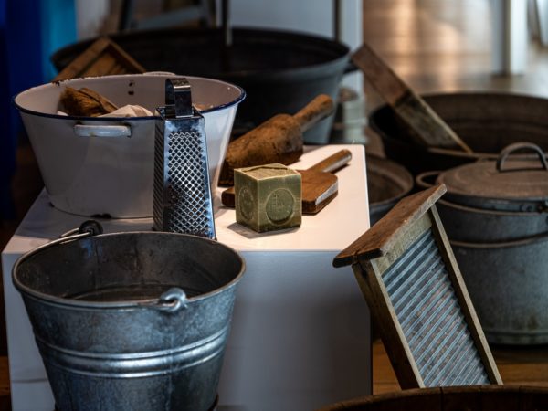 d'anciens ustensils pour la lessive - seau, cuve, planche à laver, savon et battoir - sont présentés dans une exposition.