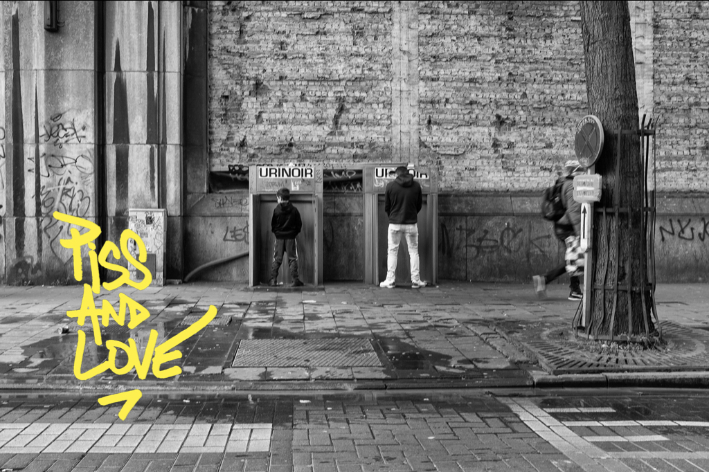 Exposition Piss & Love : un juene garçon et un homme côte à côte devant des urinoirs publics